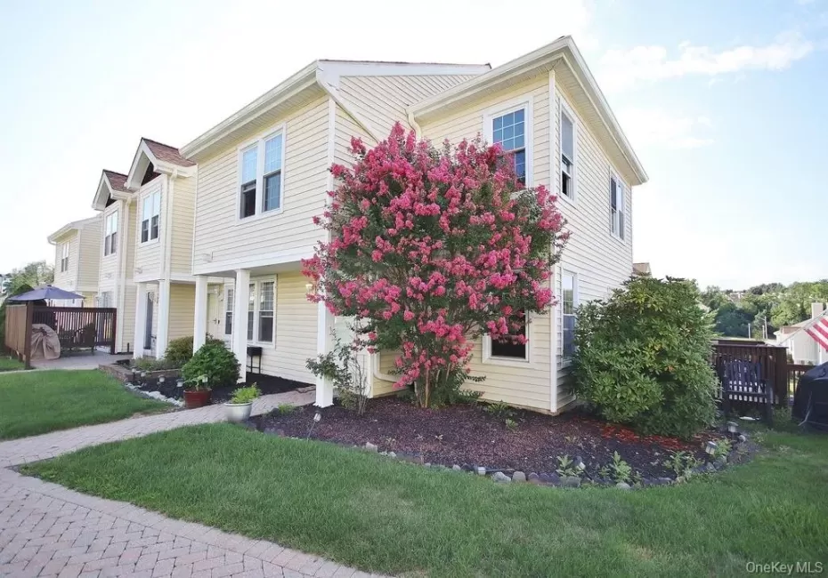 Light-colored siding exterior with white window trim and a prominent flowering tree Light-colored siding exterior with white window trim and a prominent flowering tree