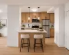 Kitchen featuring light wood cabinetry, stainless steel appliances, a white countertop island with pendant lighting, and vinyl flooring Kitchen featuring light wood cabinetry, stainless steel appliances, a white countertop island with pendant lighting, and vinyl flooring