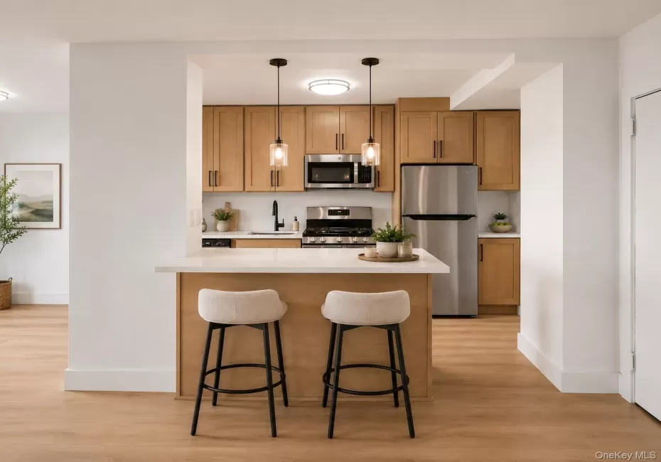 Kitchen featuring light wood cabinetry, stainless steel appliances, a white countertop island with pendant lighting, and vinyl flooring Kitchen featuring light wood cabinetry, stainless steel appliances, a white countertop island with pendant lighting, and vinyl flooring