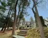 Cape cod home featuring roof with shingles and a porch Cape cod home featuring roof with shingles and a porch
