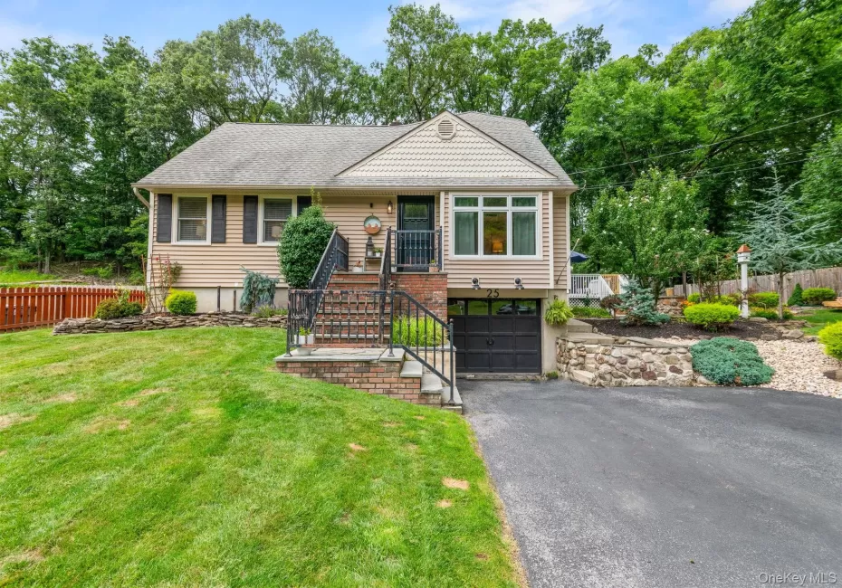 Split-level residence featuring a single-car garage, front brick steps with wrought iron railings, and a paved driveway Split-level residence featuring a single-car garage, front brick steps with wrought iron railings, and a paved driveway