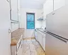 Galley kitchen featuring white cabinetry, patterned countertops, and a window Galley kitchen featuring white cabinetry, patterned countertops, and a window