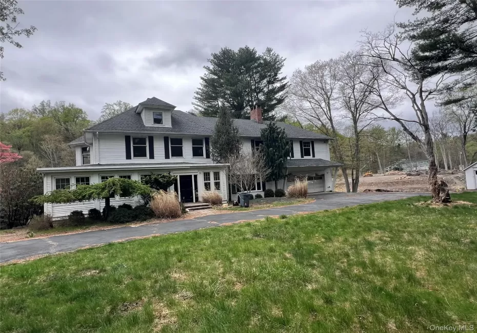 View of front of property with a front yard, driveway, an attached garage, and a chimney View of front of property with a front yard, driveway, an attached garage, and a chimney