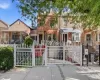 Brick facade residence featuring a white decorative metal fence and gate, an awning over the front entrance, and an additional white awning over the bay window Brick facade residence featuring a white decorative metal fence and gate, an awning over the front entrance, and an additional white awning over the bay window