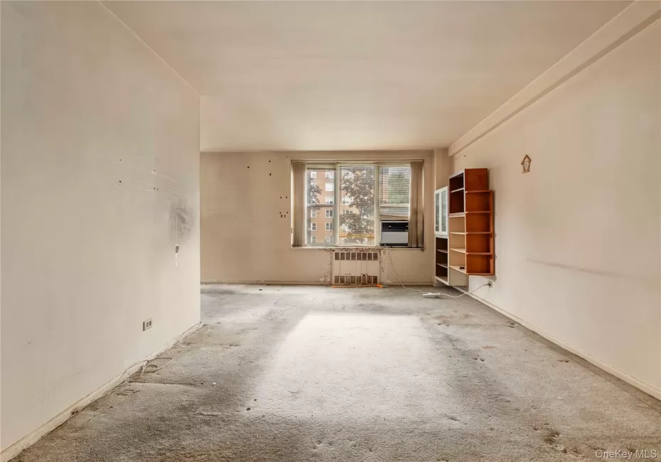 Spacious room featuring a large window, a window-mounted air conditioning unit, and a baseboard radiator Spacious room featuring a large window, a window-mounted air conditioning unit, and a baseboard radiator
