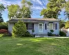 Light blue vinyl siding exterior with a shingled roof, featuring a bay window with decorative shutters, a white entry door, and manicured landscaping Light blue vinyl siding exterior with a shingled roof, featuring a bay window with decorative shutters, a white entry door, and manicured landscaping