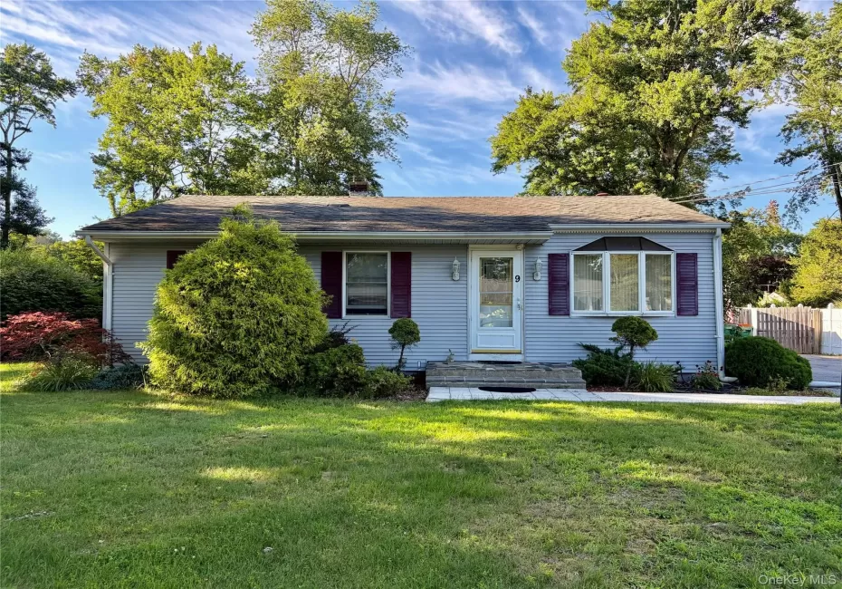 Light blue vinyl siding exterior with a shingled roof, featuring a bay window with decorative shutters, a white entry door, and manicured landscaping Light blue vinyl siding exterior with a shingled roof, featuring a bay window with decorative shutters, a white entry door, and manicured landscaping