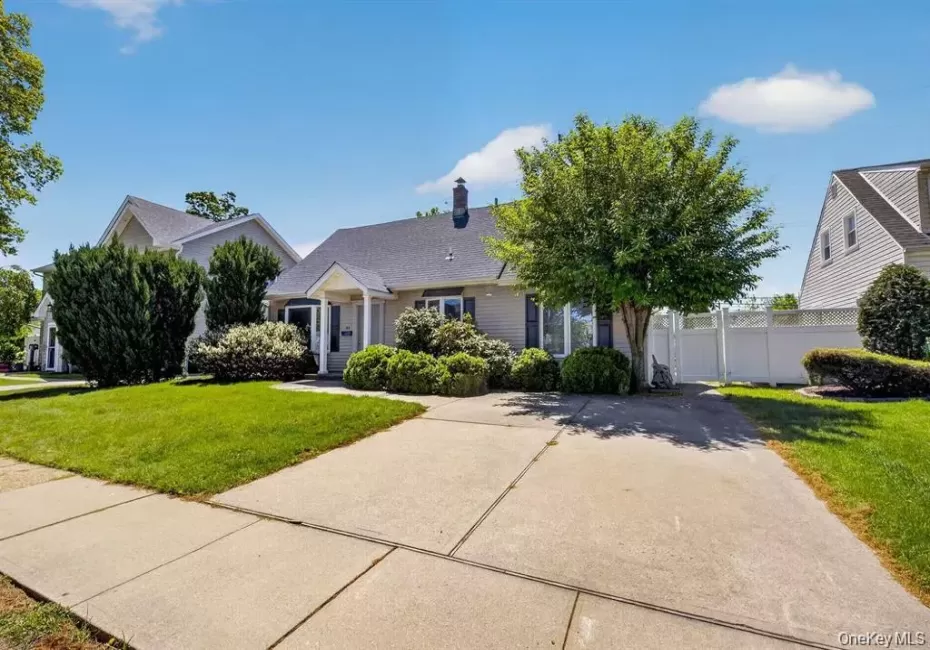 Front exterior with a concrete driveway, established landscaping, and a white privacy fence Front exterior with a concrete driveway, established landscaping, and a white privacy fence