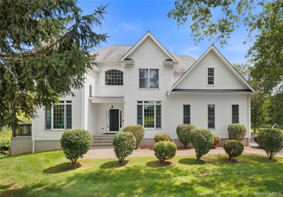 Elegant Colonial-style residence showcasing white vinyl siding, multi-gabled roofline, and a welcoming front facade. Elegant Colonial-style residence showcasing white vinyl siding, multi-gabled roofline, and a welcoming front facade.