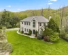 Two-story residence featuring a classic facade with a prominent arched window and a grey shingle roof Two-story residence featuring a classic facade with a prominent arched window and a grey shingle roof