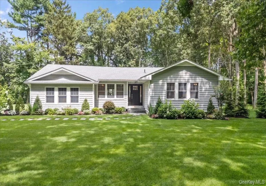 Ranch-style residence featuring grey siding, a dark entry door, and white window trim Ranch-style residence featuring grey siding, a dark entry door, and white window trim