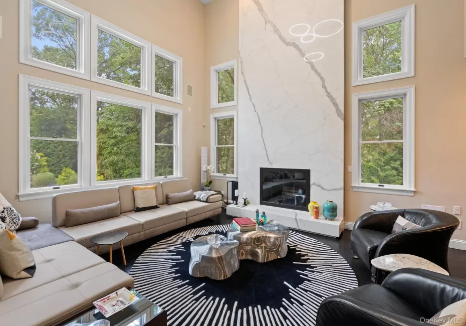 Living area with a towering ceiling, plenty of natural light, a fireplace, and wood finished floors Living area with a towering ceiling, plenty of natural light, a fireplace, and wood finished floors