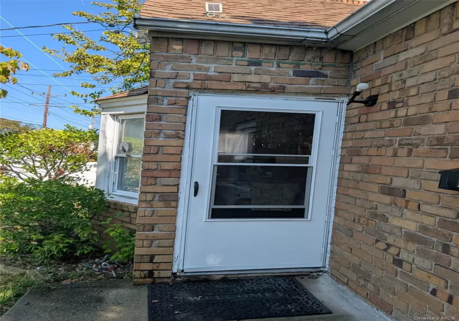 Doorway to property featuring brick siding and roof with shingles Doorway to property featuring brick siding and roof with shingles