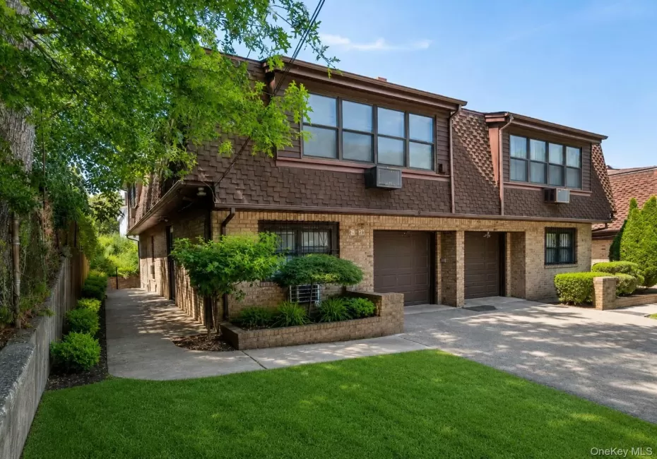 Brick exterior featuring a multi-car garage, brown shingle roof, and multiple upper-level windows Brick exterior featuring a multi-car garage, brown shingle roof, and multiple upper-level windows