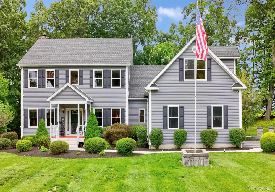 Two-story residence with legal accessory apartment featuring light gray siding, dark shutters, and a covered front porch with white railings Two-story residence with legal accessory apartment featuring light gray siding, dark shutters, and a covered front porch with white railings