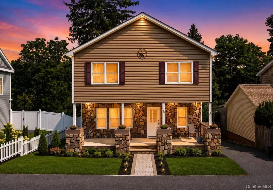 Elegant two-story home featuring a stone and siding exterior with a welcoming front porch anchored by substantial stone columns Elegant two-story home featuring a stone and siding exterior with a welcoming front porch anchored by substantial stone columns
