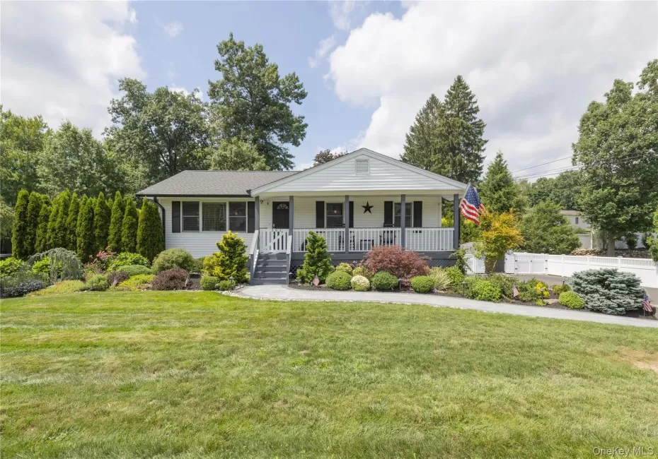 White exterior with dark shutters, front porch with white railings, grey steps, stone pathway, and landscaped garden beds White exterior with dark shutters, front porch with white railings, grey steps, stone pathway, and landscaped garden beds