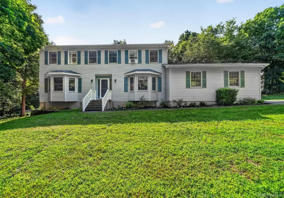 Two-story residence featuring light-toned siding and green shutters Two-story residence featuring light-toned siding and green shutters