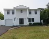 Two-story residence featuring white siding, a prominent columned entry, and a one-car garage Two-story residence featuring white siding, a prominent columned entry, and a one-car garage