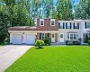 Brick and siding exterior with a two-car garage, manicured lawn, and mature trees Brick and siding exterior with a two-car garage, manicured lawn, and mature trees