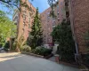 Brick multi-story building featuring multiple balconies, mature landscaping, and a covered entrance with an awning Brick multi-story building featuring multiple balconies, mature landscaping, and a covered entrance with an awning