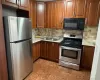 Kitchen featuring appliances with stainless steel finishes, decorative backsplash, brown cabinets, and light stone countertops Kitchen featuring appliances with stainless steel finishes, decorative backsplash, brown cabinets, and light stone countertops