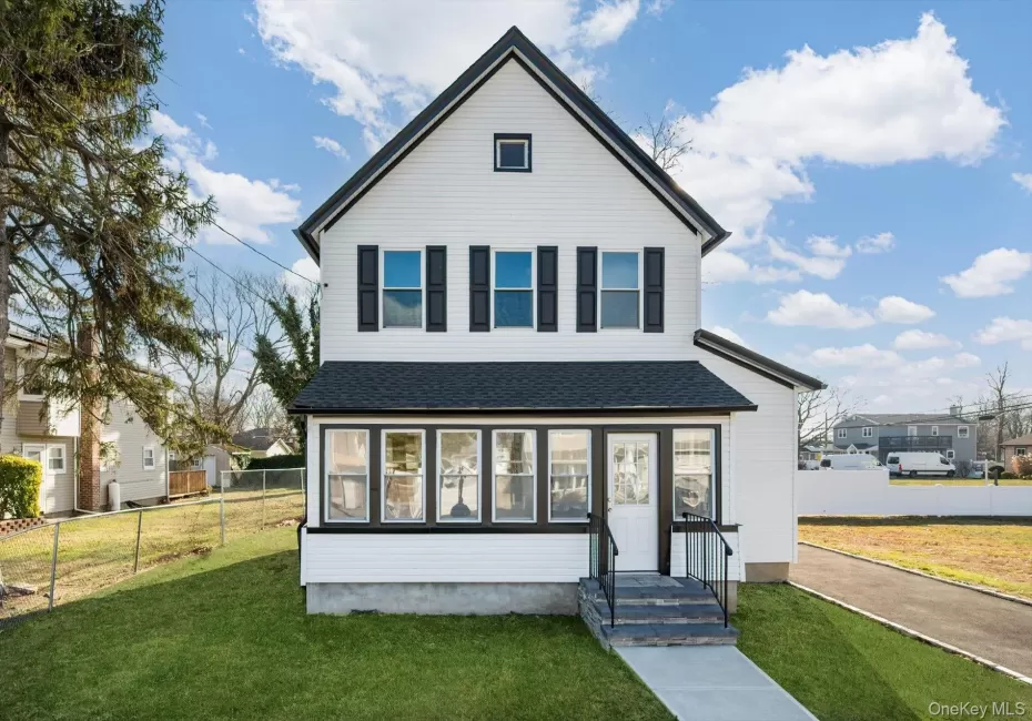 View of front of home featuring a shingled roof and a sunroom View of front of home featuring a shingled roof and a sunroom