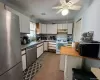 Kitchen with stainless steel appliances, light countertops, white cabinetry, light tile patterned floors, and ceiling fan Kitchen with stainless steel appliances, light countertops, white cabinetry, light tile patterned floors, and ceiling fan