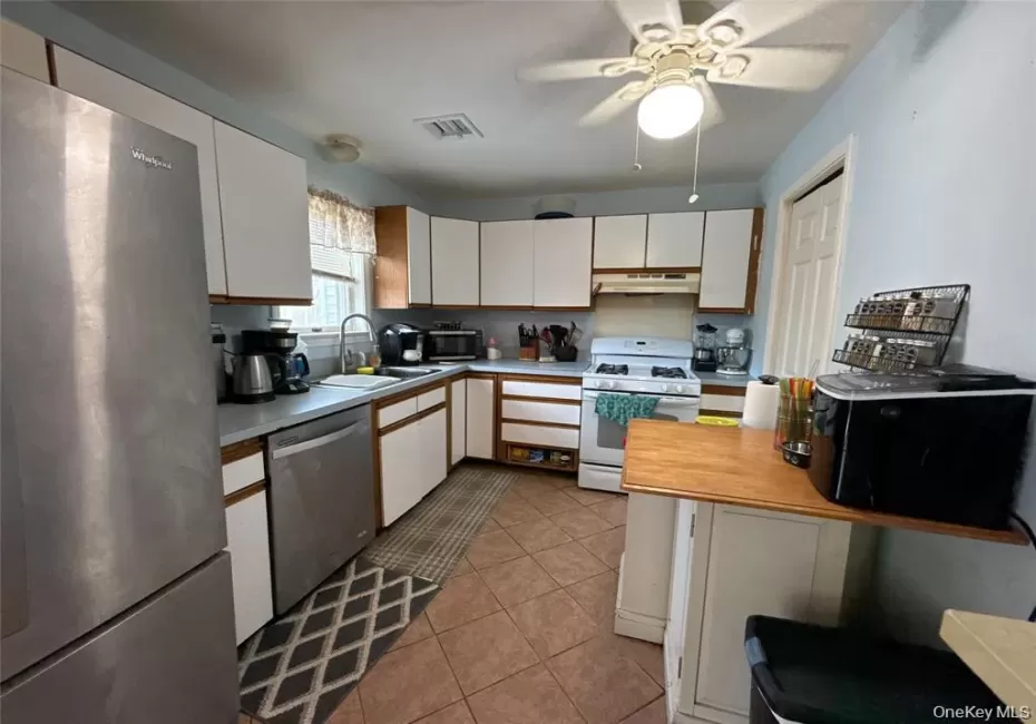 Kitchen with stainless steel appliances, light countertops, white cabinetry, light tile patterned floors, and ceiling fan Kitchen with stainless steel appliances, light countertops, white cabinetry, light tile patterned floors, and ceiling fan