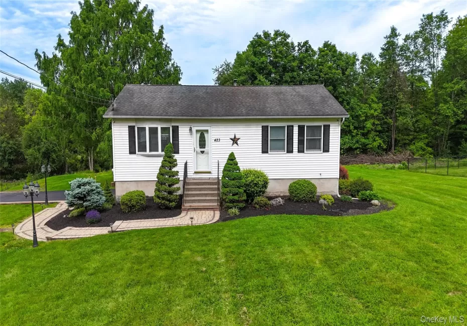 Charming raised ranch home featuring a bright white exterior with black shutters, welcoming front entry with stone steps and landscaped foundation plantings including boxwoods and evergreens Charming raised ranch home featuring a bright white exterior with black shutters, welcoming front entry with stone steps and landscaped foundation plantings including boxwoods and evergreens