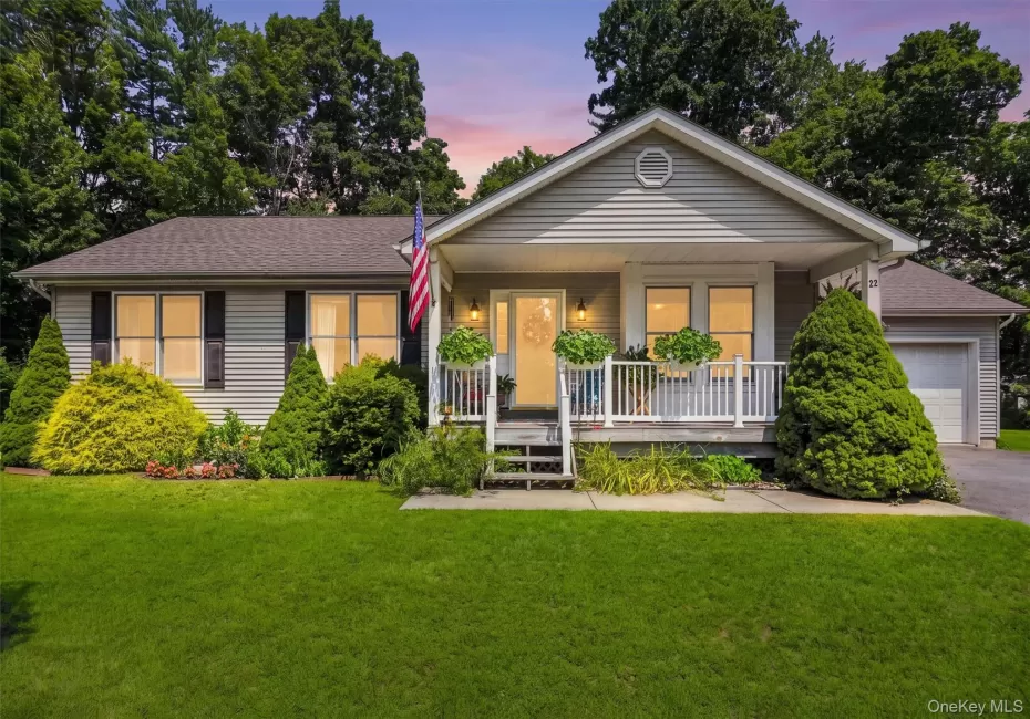 Siding exterior with a covered front porch featuring white railings, an attached garage, and a lush green lawn Siding exterior with a covered front porch featuring white railings, an attached garage, and a lush green lawn