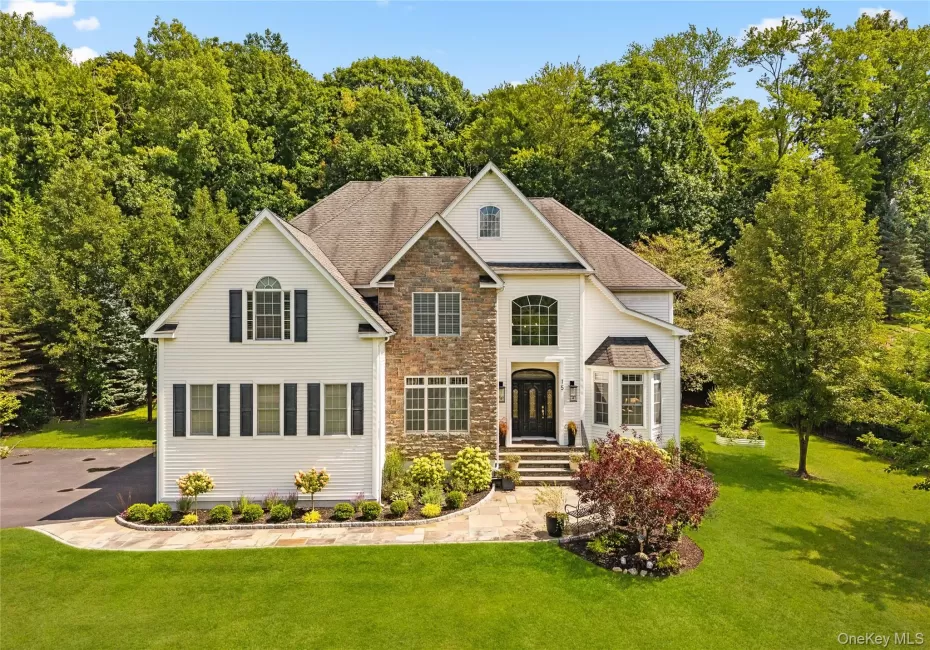 View of front of property with stone siding, a front yard, and a shingled roof View of front of property with stone siding, a front yard, and a shingled roof