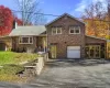 View of front facade featuring asphalt driveway, a garage, and a chimney View of front facade featuring asphalt driveway, a garage, and a chimney