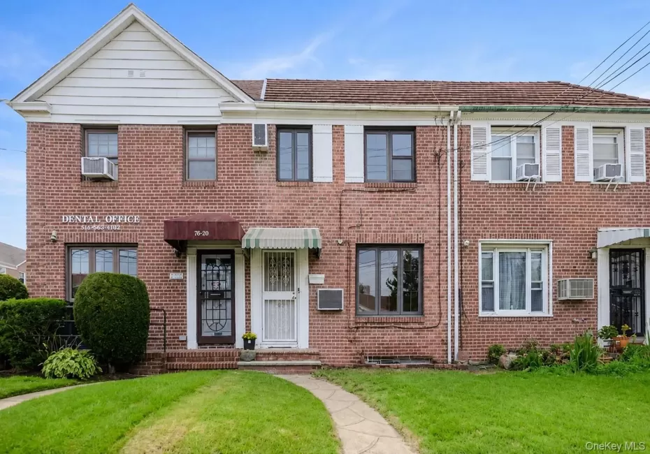 Brick facade with multiple window styles, two awnings, and a concrete pathway Brick facade with multiple window styles, two awnings, and a concrete pathway