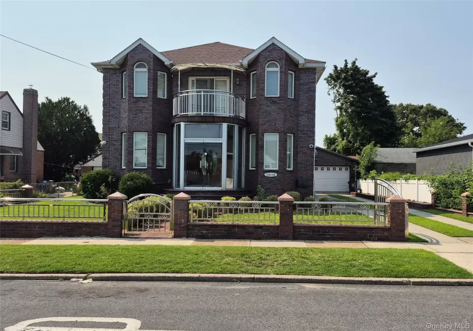 Brick exterior featuring a Juliet balcony with metal railing, arched windows, and full glass entryway with double doors. Fenced in yard with brick and metal railings and metal gates. Fully landscaped yard. Brick exterior featuring a Juliet balcony with metal railing, arched windows, and full glass entryway with double doors. Fenced in yard with brick and metal railings and metal gates. Fully landscaped yard.