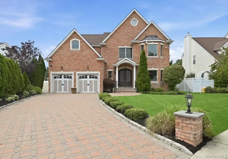 Brick exterior with a gabled roofline, two-car garage, bay window, and a paver driveway Brick exterior with a gabled roofline, two-car garage, bay window, and a paver driveway