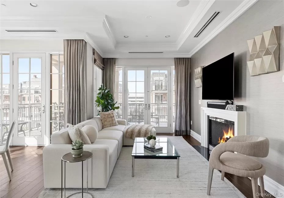 Living area featuring visible vents, ornamental molding, a lit fireplace, hardwood / wood-style flooring, and french doors Living area featuring visible vents, ornamental molding, a lit fireplace, hardwood / wood-style flooring, and french doors