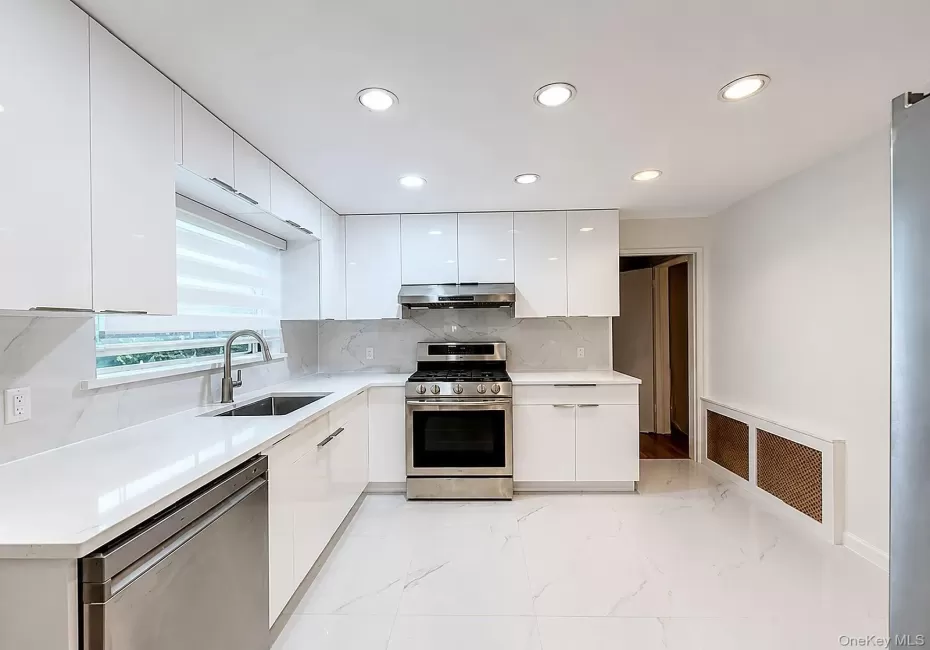 Kitchen featuring white glossy cabinetry, stainless steel appliances, recessed lighting, and white tile flooring Kitchen featuring white glossy cabinetry, stainless steel appliances, recessed lighting, and white tile flooring