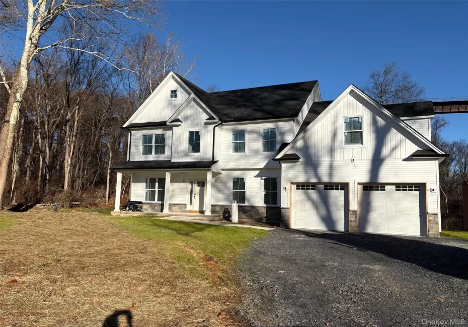 Actual house that is for sale. Modern farmhouse style home featuring stone siding, covered porch, asphalt driveway, a front lawn, and an attached garage Actual house that is for sale. Modern farmhouse style home featuring stone siding, covered porch, asphalt driveway, a front lawn, and an attached garage