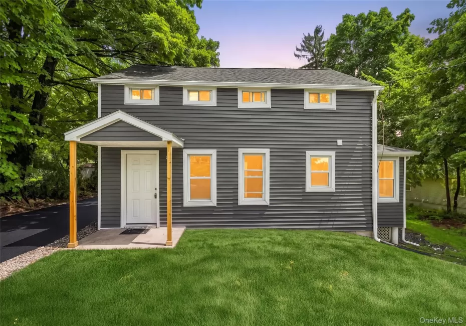 Exterior featuring dark grey horizontal siding, white trim windows, and a covered front entry with natural wood posts Exterior featuring dark grey horizontal siding, white trim windows, and a covered front entry with natural wood posts