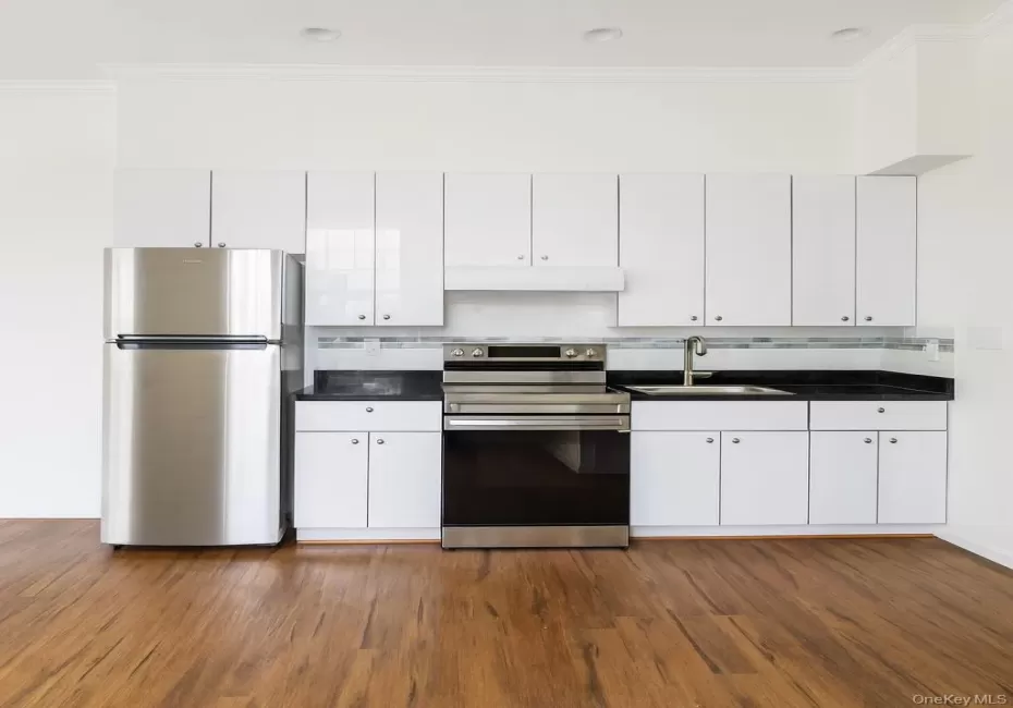 Kitchen with dark countertops, appliances with stainless steel finishes, white cabinets, backsplash, and crown molding Kitchen with dark countertops, appliances with stainless steel finishes, white cabinets, backsplash, and crown molding