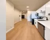 Galley kitchen featuring white cabinetry, stainless steel appliances, wood-finish flooring, and recessed lighting Galley kitchen featuring white cabinetry, stainless steel appliances, wood-finish flooring, and recessed lighting