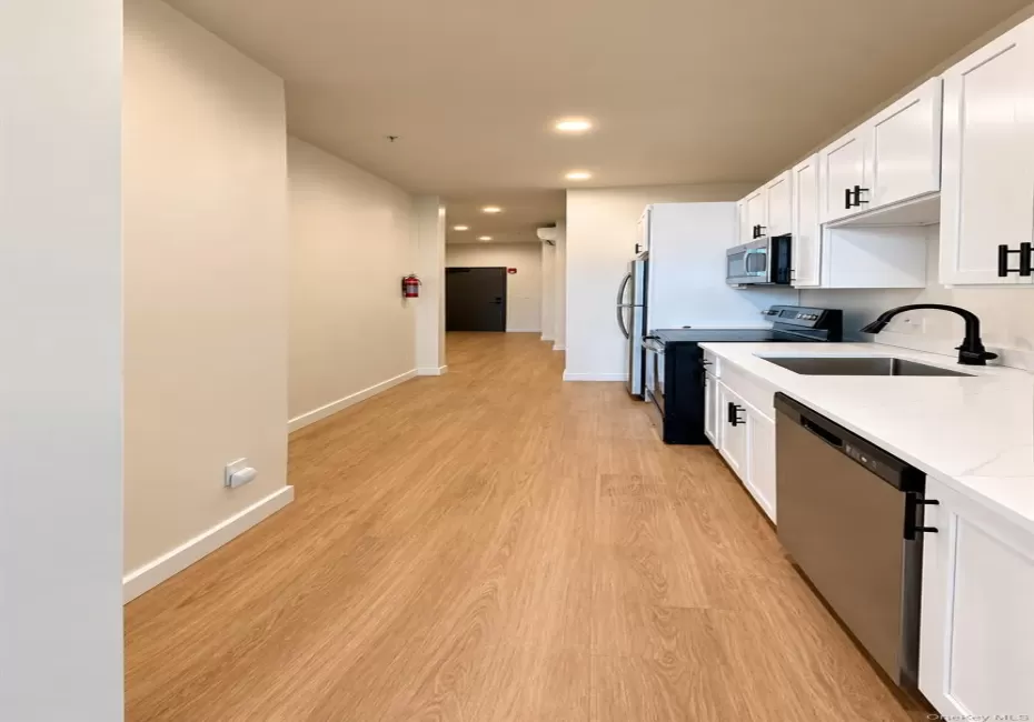Galley kitchen featuring white cabinetry, stainless steel appliances, wood-finish flooring, and recessed lighting Galley kitchen featuring white cabinetry, stainless steel appliances, wood-finish flooring, and recessed lighting