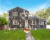 Shingle-sided exterior with a white entry door, three bay windows, black window shutters, and a well-maintained front lawn Shingle-sided exterior with a white entry door, three bay windows, black window shutters, and a well-maintained front lawn