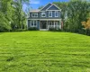 Expansive front lawn with mature trees and a two-story residence featuring a covered front porch Expansive front lawn with mature trees and a two-story residence featuring a covered front porch