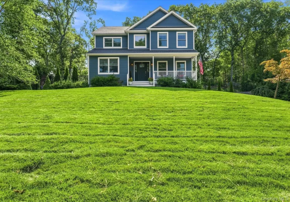 Expansive front lawn with mature trees and a two-story residence featuring a covered front porch Expansive front lawn with mature trees and a two-story residence featuring a covered front porch