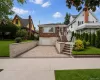 Brick exterior with a white garage door, paved driveway, and stone retaining walls Brick exterior with a white garage door, paved driveway, and stone retaining walls