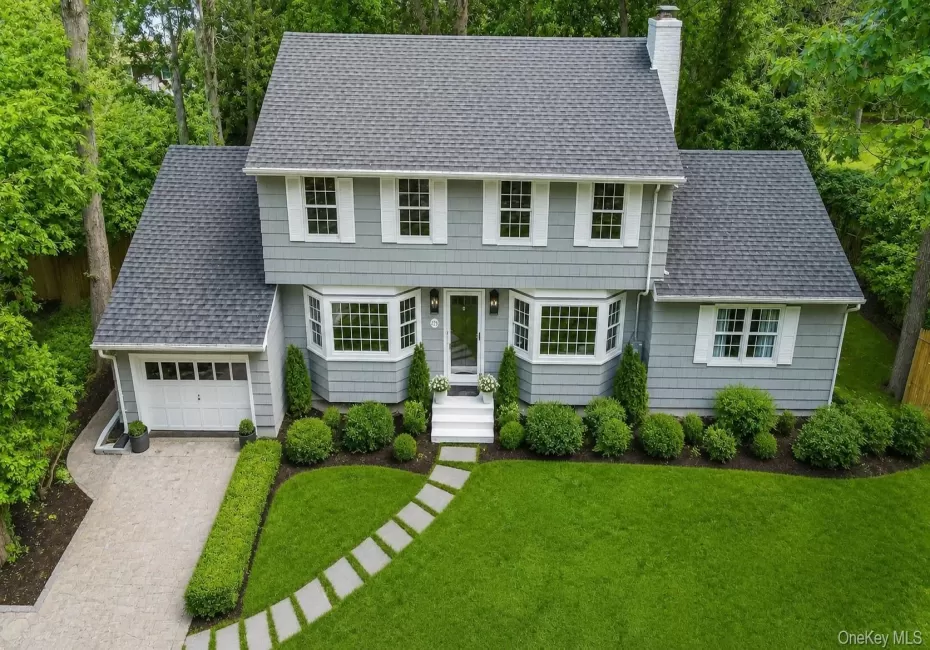 Colonial-style residence featuring a gray shingle exterior, bay windows, and a gray shingle roof Colonial-style residence featuring a gray shingle exterior, bay windows, and a gray shingle roof