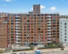 Brick facade building with multiple balconies, a ground-level entrance canopy, and structured landscaping Brick facade building with multiple balconies, a ground-level entrance canopy, and structured landscaping