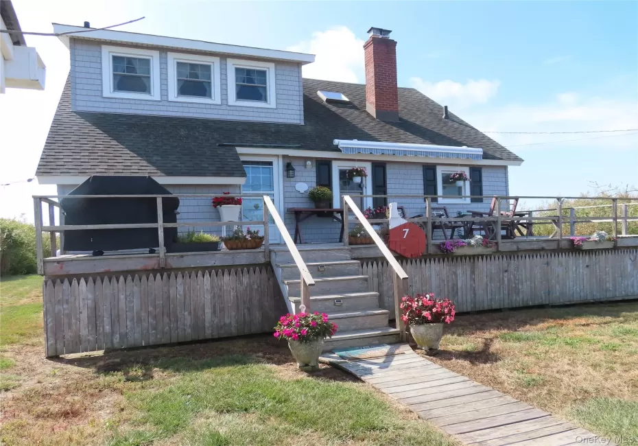 Rear view of house featuring a wooden deck, roof with shingles, a chimney, and stairs Rear view of house featuring a wooden deck, roof with shingles, a chimney, and stairs